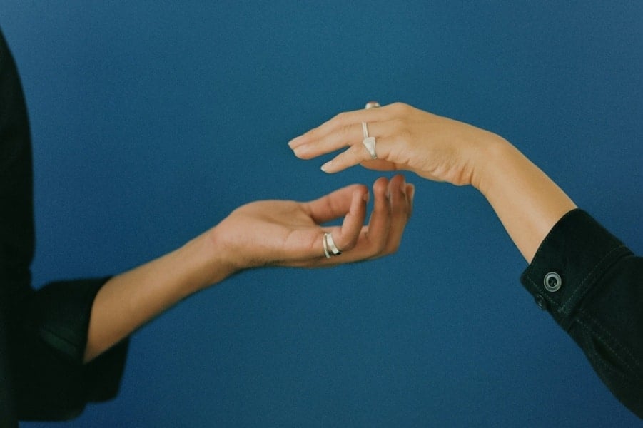 Two hands hover close, showcasing the couple's rings, symbolizing both love and codependency.