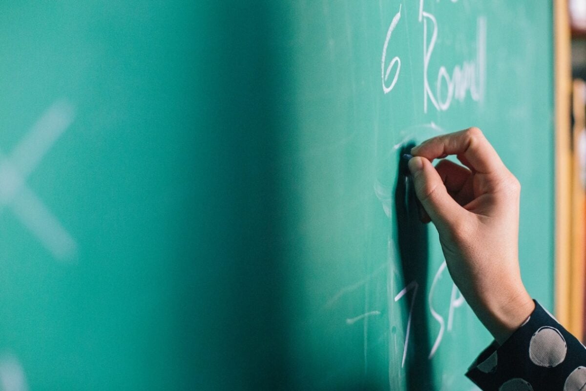 A person writes on a blackboard with chalk, demonstrating how to help a child with a learning disability.