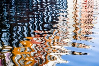 Reflection of urban buildings in rippling water, illustrating the challenges of helping someone with schizophrenia