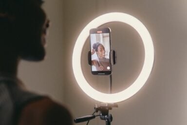 A woman poses for a selfie using a smartphone, with a radiant light ring providing flattering illumination, illustrating how to build confidence.