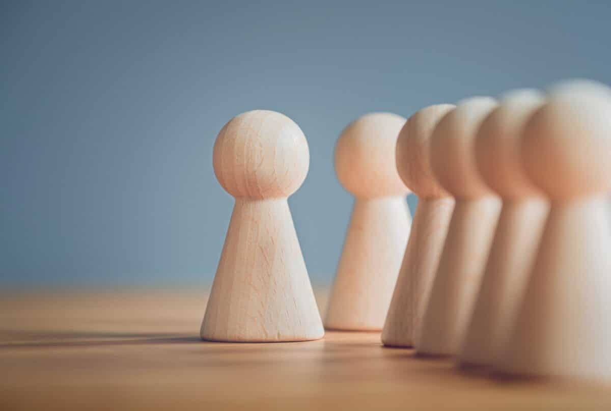 A row of wooden figurines arranged neatly, showcasing orderliness and craftsmanship, illustrating symptoms of obsessive-compulsive personality disorder (OCPD).