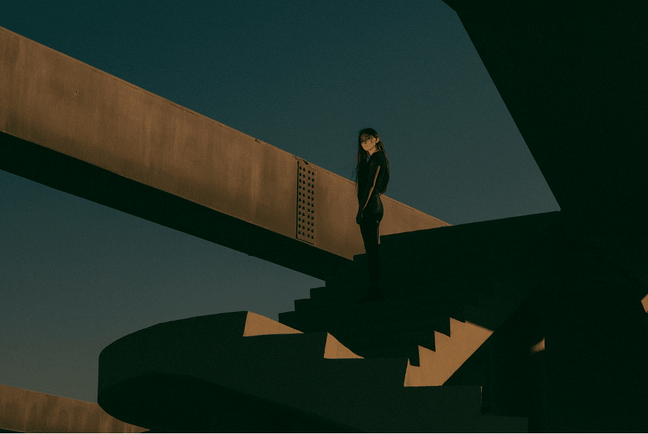 A solitary person stands on a concrete stairway in a minimalist urban setting, wondering how to deal with anxiety.